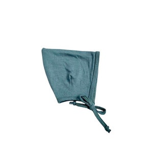 May include: A soft, blue baby bonnet with a tie. The bonnet is made of a stretchy fabric and has a simple design.