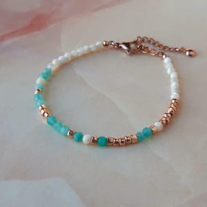 May include: A delicate bracelet with white and turquoise beads, accented with rose gold accents. The bracelet features a lobster clasp closure.