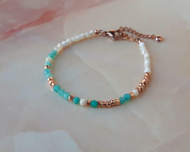 May include: A delicate bracelet with white and turquoise beads, accented with rose gold accents. The bracelet features a lobster clasp closure.