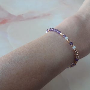 Op de afbeelding: Een delicate armband met afwisselende paarse en witte kralen op een ros&eacute;gouden ketting.