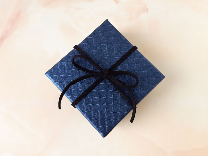 May include: A dark blue gift box with a black velvet ribbon tied in a bow.