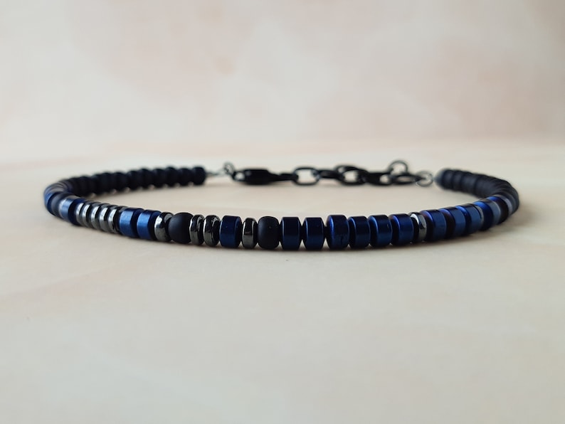 May include: A beaded bracelet with black and blue beads. The bracelet has a silver clasp.