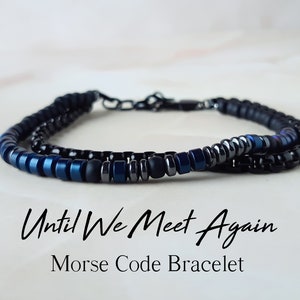 May include: A black and blue beaded bracelet with the text "Until We Meet Again" and the words "Morse Code Bracelet" below.