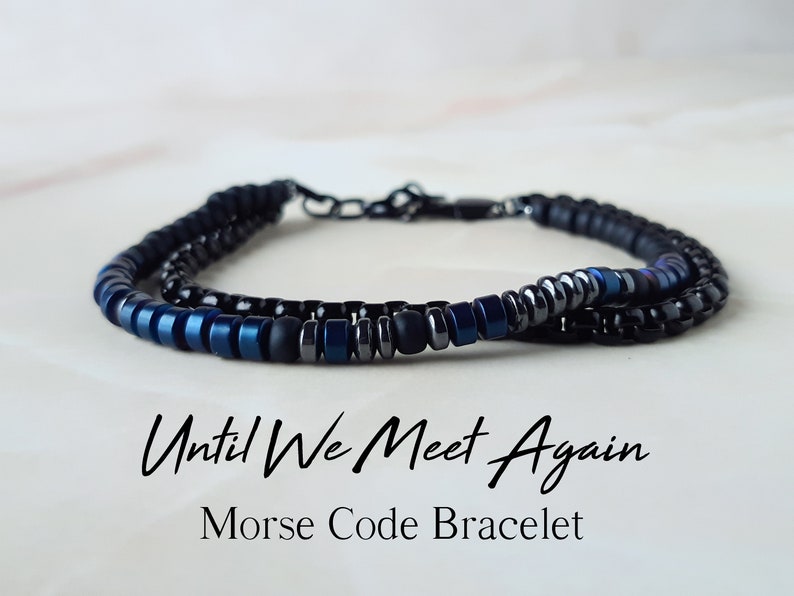 May include: A black and blue beaded bracelet with the text "Until We Meet Again" and the words "Morse Code Bracelet" below.