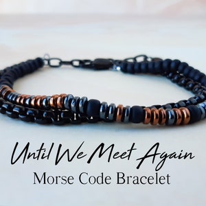 May include: A layered Morse code bracelet with black and copper-coloured beads. The bracelet features the text "Until We Meet Again" and "Morse Code Bracelet". The jewellery is designed for everyday wear.