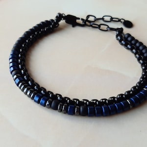 May include: A black and blue beaded bracelet with a black metal clasp.