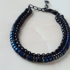 May include: A black and blue beaded bracelet with a metal clasp. The bracelet is made with small, round beads in black and blue.