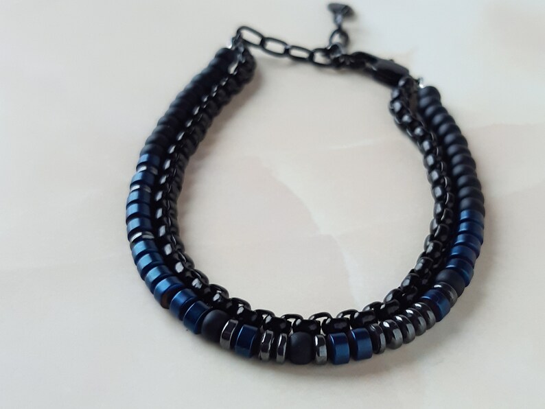 May include: A black and blue beaded bracelet with a metal clasp. The bracelet is made with small, round beads in black and blue.