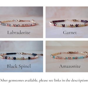 May include: Four bracelets with different gemstones: labradorite, garnet, black spinel, and amazonite. Each bracelet has a rose gold chain and white beads.