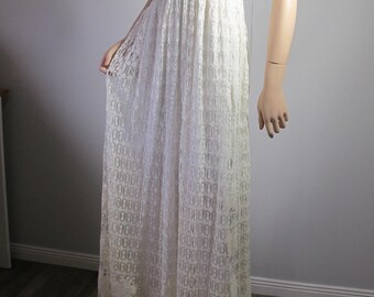 May include: A white crochet maxi dress with a V-neckline and spaghetti straps. The dress has a fitted bodice and a flowing skirt.
