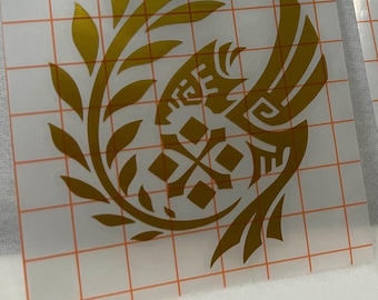 May include: Two vinyl decals featuring a stylized bird design. One is gold, the other is gray. Both are on a clear backing with a grid pattern. The bird design includes a circular shape with leaves and geometric elements.