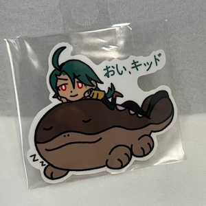 May include: A sticker featuring a cartoon character with green hair and red eyes, resting on a brown, sleeping creature. The sticker has Japanese text and is sealed in a clear plastic bag.