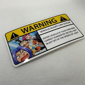 May include: A rectangular sticker with a yellow and black border. The sticker features a cartoon image and the text "WARNING" and "SERIOUS INJURY CAN OCCUR". Additional text reads "ENTER VEHICLE AT YOUR OWN RISK I CANNOT GUARANTEE WE WILL NOT BLAST OFF AT THE SPEED OF LIGHT".