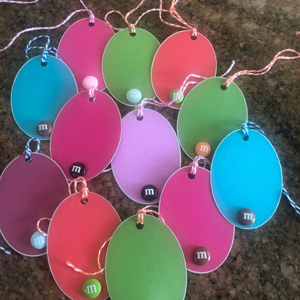 M&M gift tags! Fun, colorful oval tags embellishment with a single dimensional candy, hand edged in silver metallic, vibrant cotton twine.