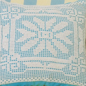 May include: White crocheted pillow with a blue background. The pillow has a delicate, intricate design.
