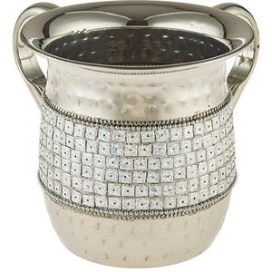 Pode incluir: Uma jarra de metal prateado com acabamento martelado e uma faixa decorativa de quadrados brancos ao redor do meio.