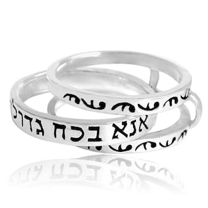 Puede incluir: Dos anillos de plata con texto hebreo inscrito en ellos. Los anillos están apilados uno encima del otro.
