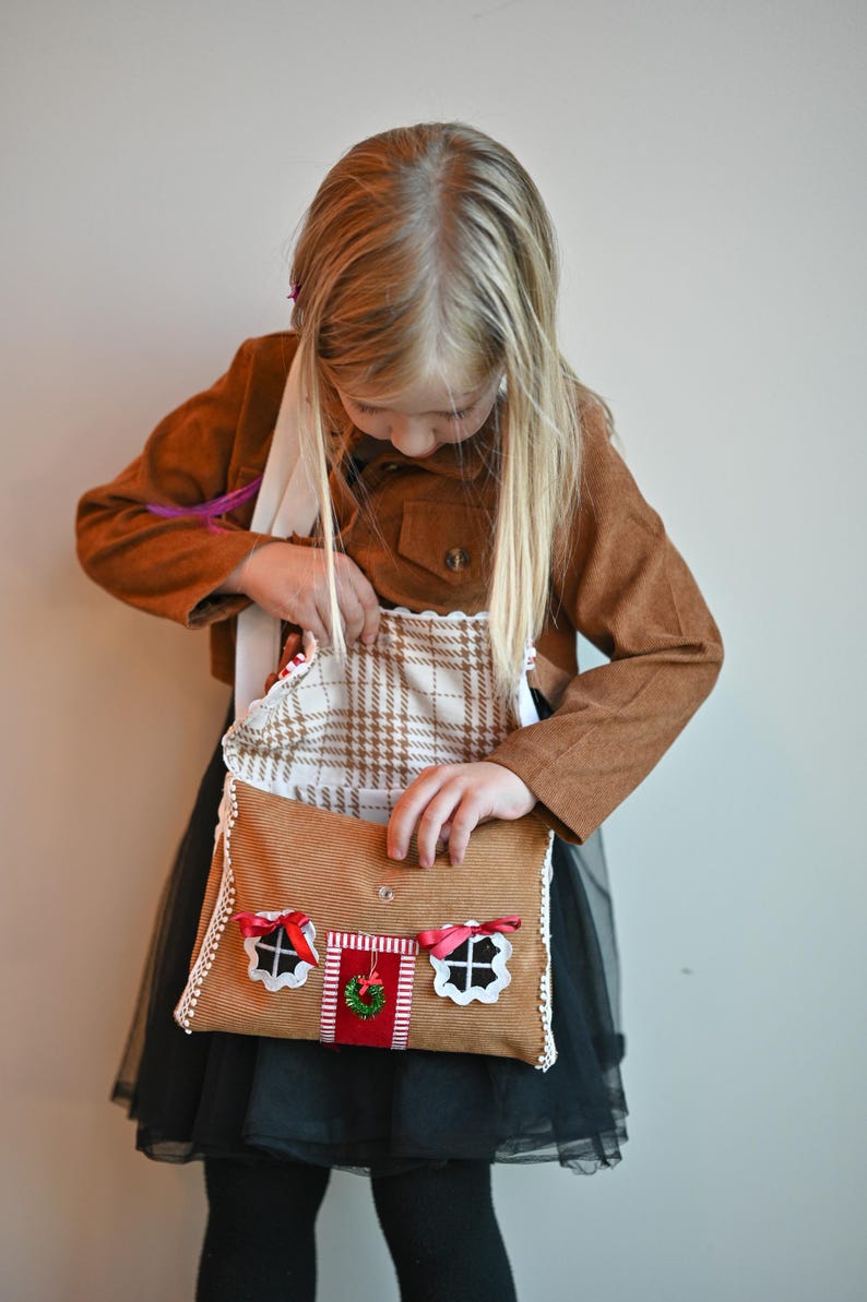 A girl is opening a Gingerbread House Christmas Purse – Peppermint Candy Holiday Crossbody Bag.