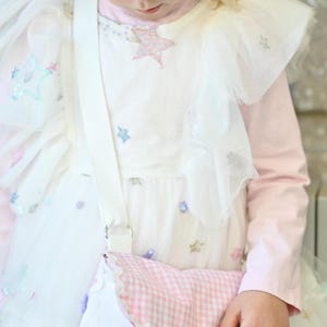The girl is wearing a Fairy Cottage House Purse –  Crossbody Bag