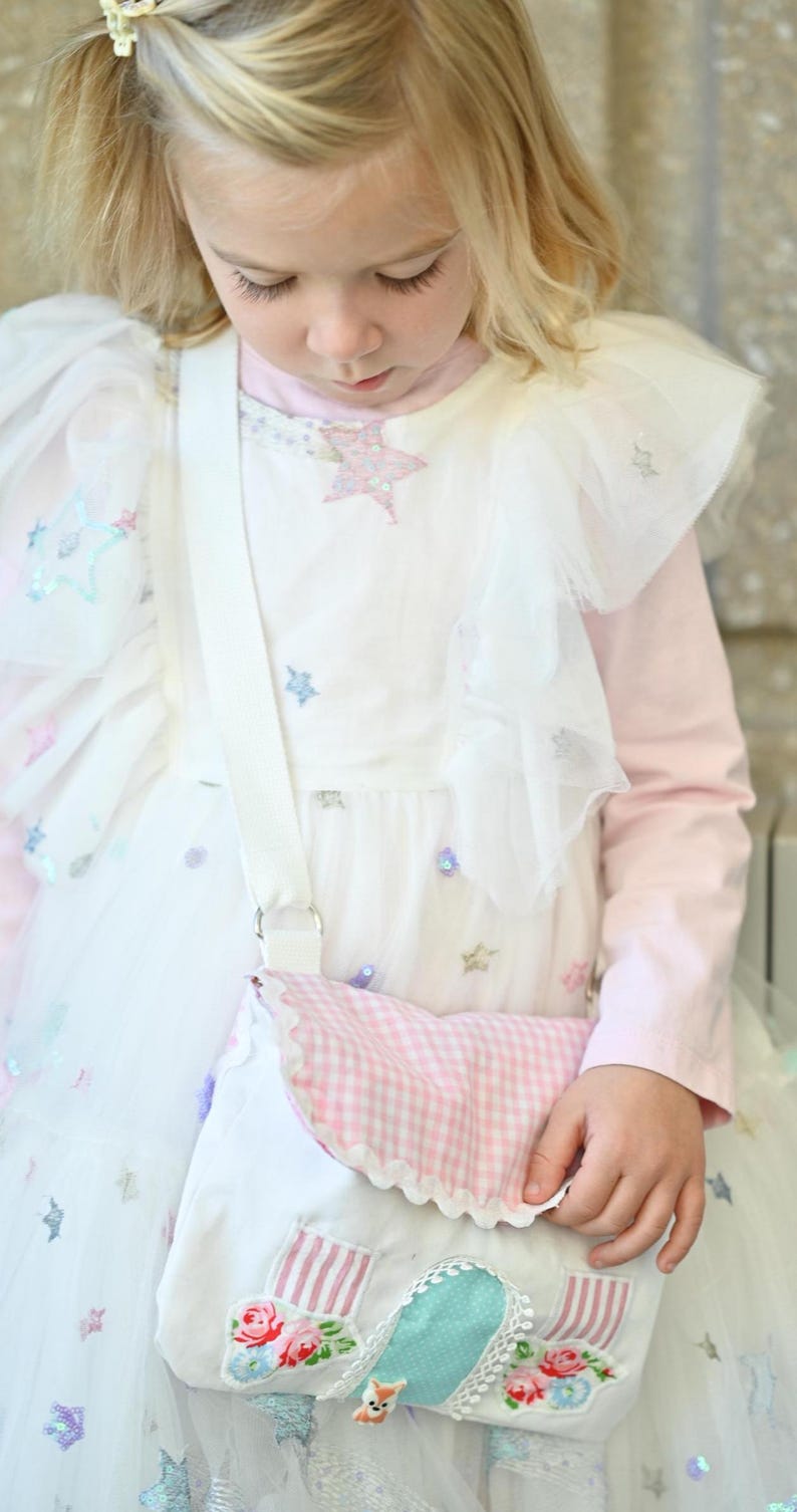 The girl is wearing a Fairy Cottage House Purse –  Crossbody Bag