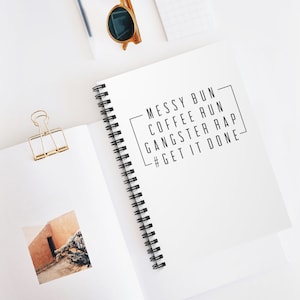 May include: A white spiral bound notebook with the text "MESSY BUN - COFFEE RUN - GANGSTER RAP - #GET IT DONE" printed in black.