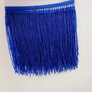 May include: Royal blue beaded fringe trim. The fringe is made of small, round beads that are strung together to create a long, flowing fringe. The trim is perfect for adding a touch of elegance to any project.