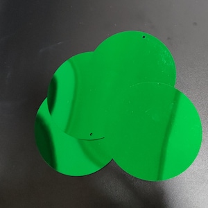 Peut inclure: Trois paillettes rondes, métalliques et vertes.