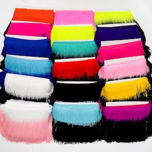 Könnte beinhalten: Sortiment an bunten Fransenbesatz in verschiedenen Farben, darunter Pink, Blau, Grün, Gelb, Rot, Weiß und Schwarz. Die Fransen sind in Reihen angeordnet, wobei jede Reihe eine andere Farbe aufweist.