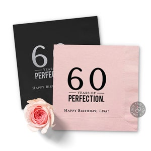 Puede incluir: Dos servilletas de papel rosa y negro con el texto "60 a&ntilde;os de perfecci&oacute;n. &iexcl;Feliz cumplea&ntilde;os, Lisa!" impreso en ellas.