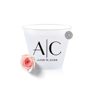 May include: White plastic cup with black lettering that says "A|C" and "JUNE 15, 2028". A single pink rose is in the foreground.