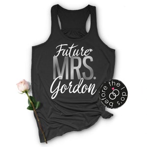 May include: Black tank top with the text "Future Mrs. Gordon" in silver and white lettering. A diamond ring icon is above the word "Mrs."