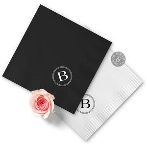 May include: Two paper napkins, one black and one white, with a circle monogram of the letter "B" in white on the black napkin and black on the white napkin.
