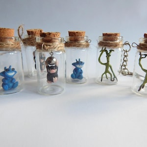 May include: Six small glass jars with cork tops and a variety of small figurines inside. The jars are decorated with twine and have a metal loop for hanging.