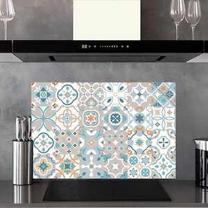 Pode incluir: Um protetor de respingos de cozinha com um padrão geométrico colorido em tons de azul, branco e laranja. O protetor de respingos é feito de vidro e tem um design moderno.