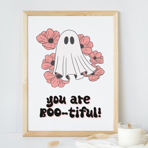 Puede incluir: Un fantasma blanco con dos ojos negros est&aacute; rodeado de flores rosas. El texto "you are boo-tiful!" est&aacute; escrito debajo del fantasma.
