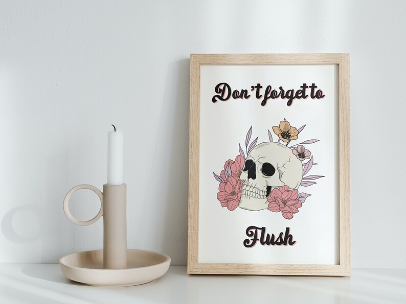 Puede incluir: Una impresi&oacute;n enmarcada con fondo blanco y una calavera en blanco y negro con flores rosas y amarillas. El texto "No olvides tirar de la cadena" est&aacute; escrito en letras cursivas negras.