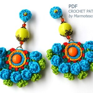 May include: Crochet earrings with a colorful floral design, featuring blue, green, orange, yellow, and red accents. The earrings are adorned with beads and a large, round, yellow bead.