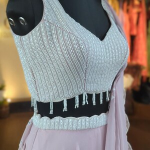 May include: A dusty rose colored skirt with a beaded waistband and a matching beaded top with a V-neckline.