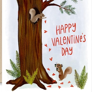 May include: Valentine's Day greeting card featuring a brown tree with two squirrels and red heart accents. The card reads "Happy Valentine's Day" in red text. A beige envelope is included.
