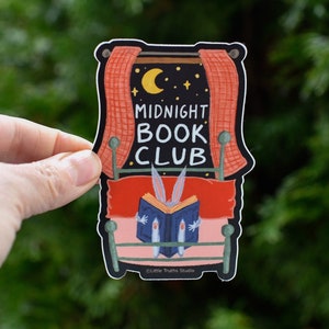 Vinyl Sticker that says Midnight Book Club. Cute sticker of a rabbit reading a book in bed, with a window and moon and stars.