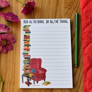 May include: A white notepad with a stack of books, a red armchair, and a cup of coffee. The notepad has lined paper and the text "Read all the books. Do all the things." at the top.