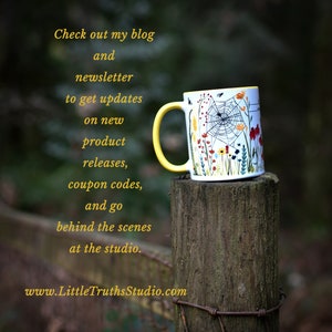 May include: A yellow and white ceramic mug with a floral and spiderweb design. The mug is sitting on a wooden post with a wire fence in the background. The text on the mug reads "Check out my blog and newsletter to get updates on new product releases, coupon codes, and go behind the scenes at the studio. www.LittleTruthsStudio.com"