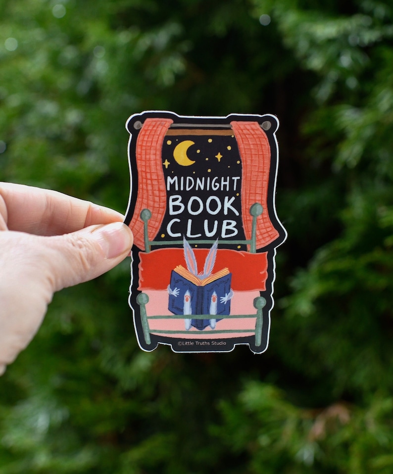 Vinyl Sticker that says Midnight Book Club. Cute sticker of a rabbit reading a book in bed, with a window and moon and stars.