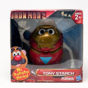 May include: A Mr. Potato Head toy in a box, designed as Iron Man. The toy is red and gold, with white arms and a helmet. The box reads "Iron Man 2" and "Tony Starch."