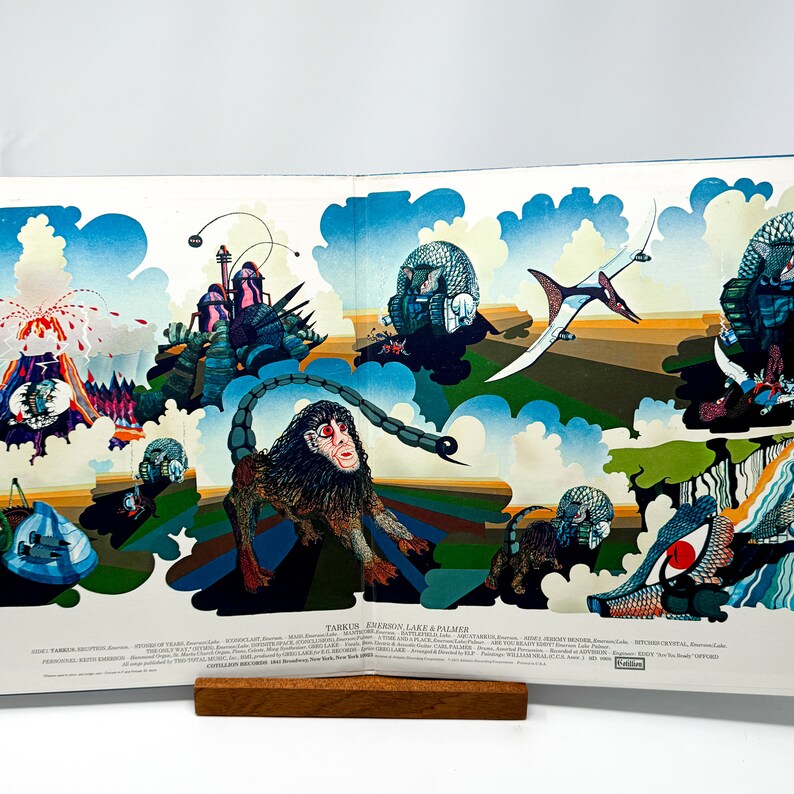 Puede incluir: Una portada de &aacute;lbum colorida con un dise&ntilde;o psicod&eacute;lico que presenta un mono, un volc&aacute;n y una variedad de otras criaturas. El t&iacute;tulo del &aacute;lbum es "Tarkus" de "Emerson, Lake & Palmer".
