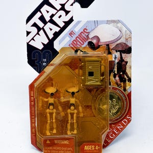 May include: A Star Wars Pit Droids action figure set in a clear plastic package. The package features the Star Wars logo, the text "A LONG TIME AGO IN A GALAXY FAR, FAR AWAY...", and the warning "CHOKING HAZARD-Small parts. Not for children under 3 years."