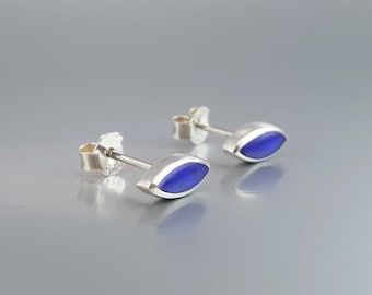 May include: A pair of silver stud earrings with a blue oval-shaped gemstone.