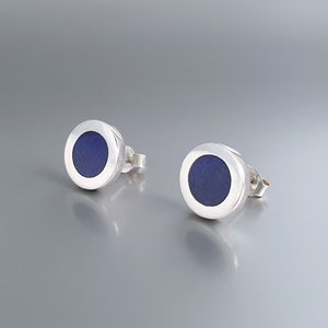 Könnte beinhalten: Ein Paar silberne Ohrstecker mit einem runden blauen Lapislazuli-Stein in der Mitte jedes Ohrsteckers.