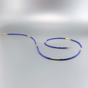 May include: A blue and gold necklace made of small, round beads. The necklace is made of lapis lazuli and gold.