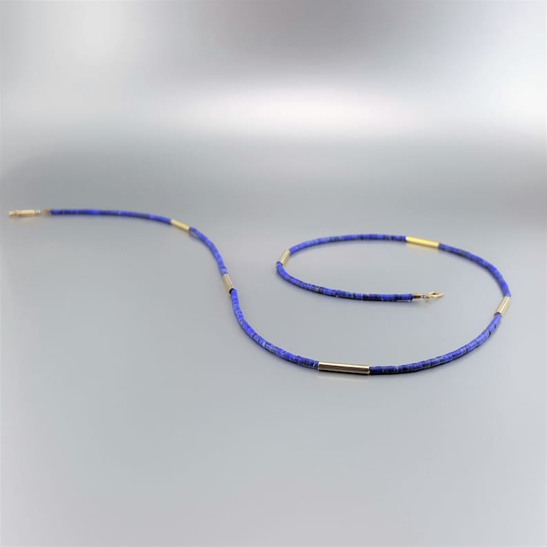 May include: A blue and gold necklace made of small, round beads. The necklace is made of lapis lazuli and gold.